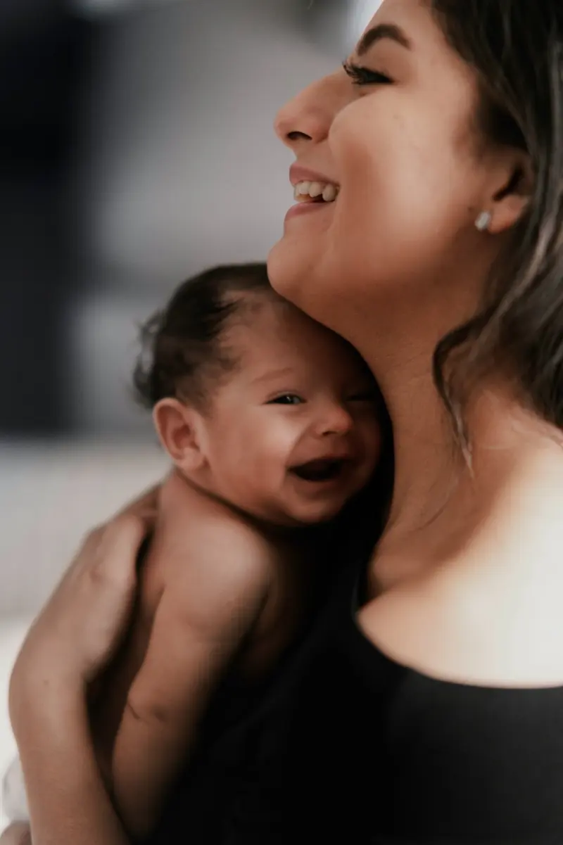 Une maman qui rit, son bébé blotti dans son cou