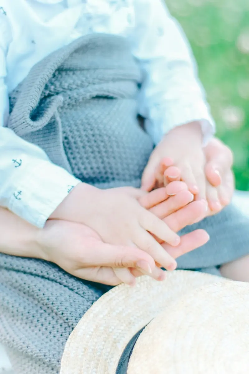 Des petites mains d'enfant posées dans celles de sa mère