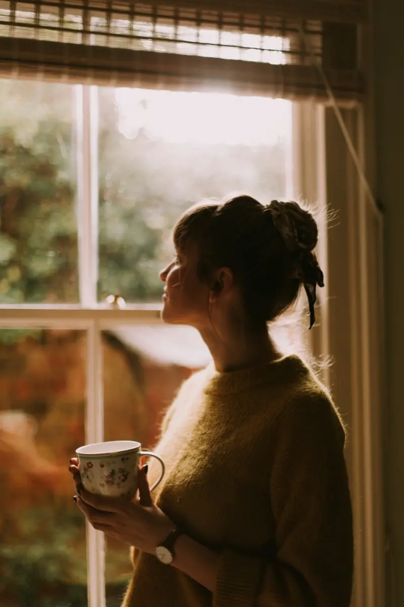 Une femme à la fenêtre, une tasse entre les mains, un instant pour elle