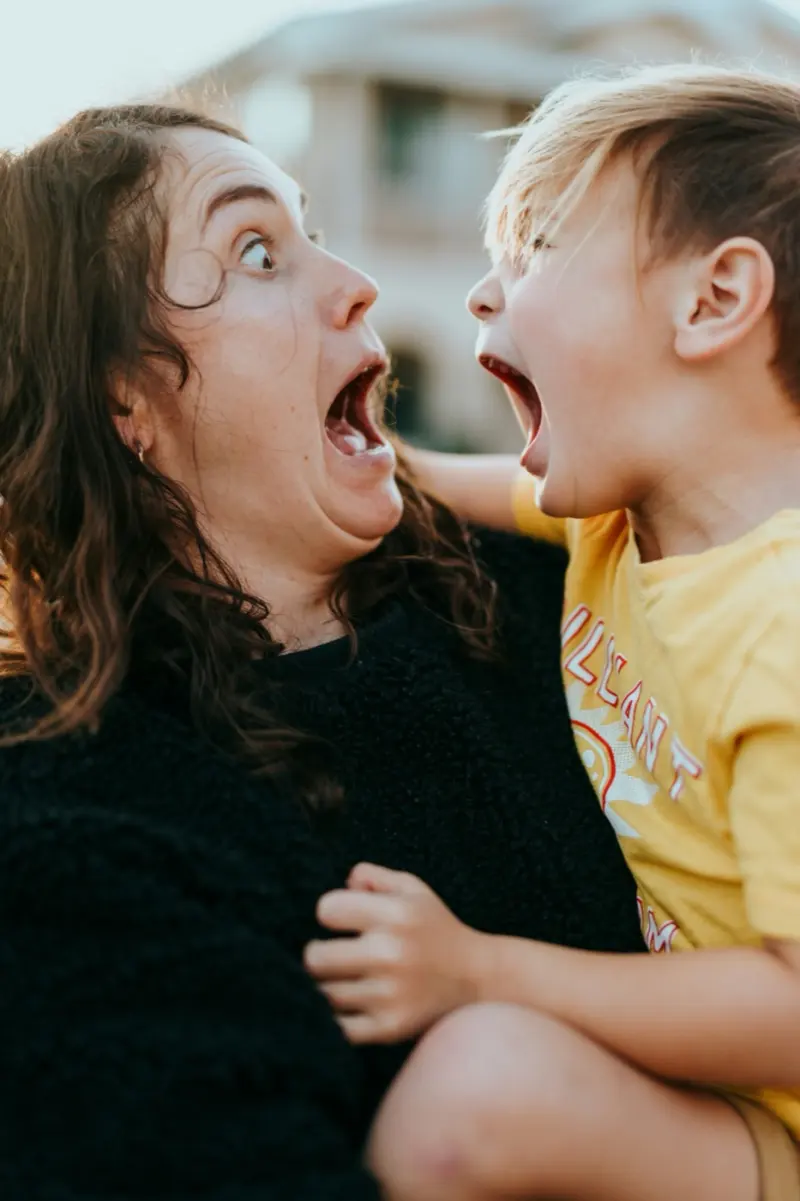 Une maman et son fils qui crient de rire face à face